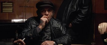 Movie still from “Little Odessa” (1994), directed by James Gray – A man sitting in a chair smoking a cigarette; Medium shot, Low angle