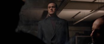 Movie still from “Little Odessa” (1994), directed by James Gray – A man in a suit standing in a dark room; Medium shot, Low angle