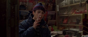 Movie still from “Little Odessa” (1994), directed by James Gray – A young man smoking a cigarette in front of magazines; Close Up shot, Low angle