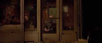 Movie still from “Little Odessa” (1994), directed by James Gray – A man sitting in an open window looking out at the street; Wide shot, High angle