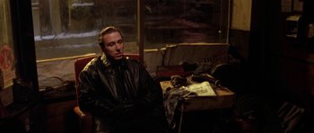 Movie still from “Little Odessa” (1994), directed by James Gray – A man sitting in front of a table with a guitar; Medium shot, High angle