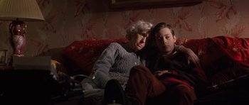Movie still from “Little Odessa” (1994), directed by James Gray – An older woman and a young boy are sitting on a couch; Medium shot, High angle