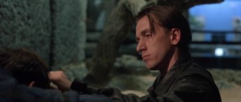 Movie still from “Little Odessa” (1994), directed by James Gray – A man sitting in front of a stone wall; Close Up shot, Low angle