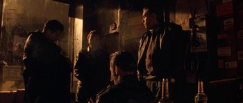 Movie still from “Little Odessa” (1994), directed by James Gray – A group of men standing next to each other in a room; Medium shot, Over the shoulder angle