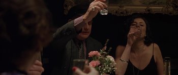 Movie still from “Little Odessa” (1994), directed by James Gray – A man in a suit and tie holding a glass of wine; Medium shot, Over the shoulder angle