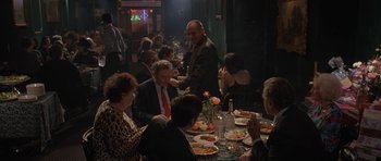 Movie still from “Little Odessa” (1994), directed by James Gray – A group of people sitting at a table with plates of food on it; Wide shot, Over the shoulder angle