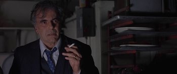 Movie still from “Little Odessa” (1994), directed by James Gray – An older man smoking a cigarette in a dark room; Close Up shot, Low angle