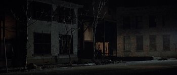 Movie still from “Little Odessa” (1994), directed by James Gray – A building that has been boarded up at night; Wide shot, Over the shoulder angle