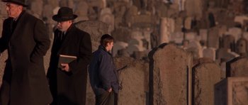 Movie still from “Little Odessa” (1994), directed by James Gray – A man standing in front of a group of tombstones; Wide shot, Over the shoulder angle