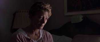 Movie still from “Little Odessa” (1994), directed by James Gray – An older woman sitting on a bed in a dark room; Close Up shot, Over the shoulder angle