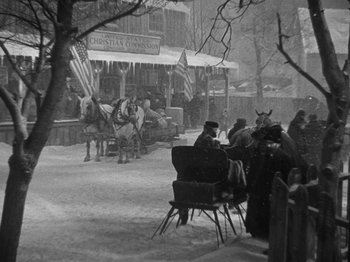 Movie still from “Little Women” (1933), directed by George Cukor – A black and white photo of people sitting at a table outside; Wide shot, High angle