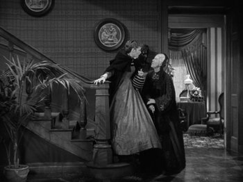 Movie still from “Little Women” (1933), directed by George Cukor – A couple of women standing next to each other on stairs; Wide shot, High angle