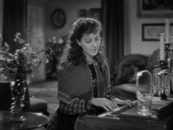 Movie still from “Little Women” (1933), directed by George Cukor – A woman sitting at a table playing a piano; Medium shot, High angle
