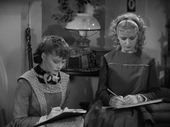 Two women are writing on a notebook