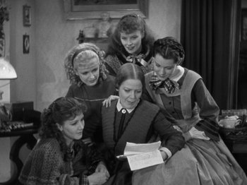 Movie still from “Little Women” (1933), directed by George Cukor – A group of young women looking at a piece of paper; Medium shot, High angle