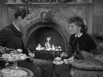 Movie still from “Little Women” (1933), directed by George Cukor – A man and a woman sitting in front of a fireplace; Medium shot, High angle