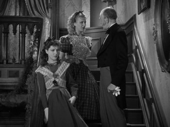 Movie still from “Little Women” (1933), directed by George Cukor – Two women and a man standing on the stairs; Medium shot, High angle