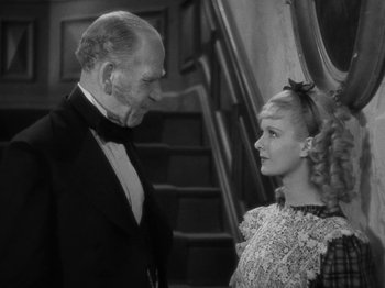 Movie still from “Little Women” (1933), directed by George Cukor – An older man and a young woman standing next to each other in front of a staircase; Medium shot, High angle