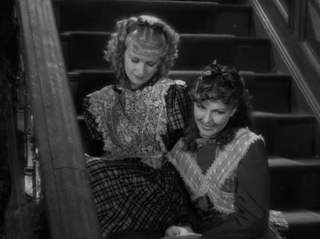 Movie still from “Little Women” (1933), directed by George Cukor – Two women sitting on the stairs looking at a phone; Medium shot, High angle