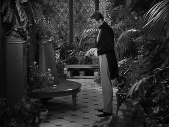 Movie still from “Little Women” (1933), directed by George Cukor – A black and white photo of a man standing in a garden; Wide shot, High angle