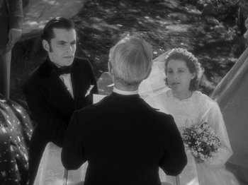 Movie still from “Little Women” (1933), directed by George Cukor – A man and a woman are standing next to each other in front of another man; Medium shot, Over the shoulder angle