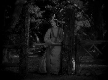 Movie still from “Little Women” (1933), directed by George Cukor – A man in native american garb standing next to a wooden fence; Wide shot, High angle