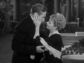 Movie still from “Little Women” (1933), directed by George Cukor – A man and a woman standing next to each other in front of trees; Medium shot, High angle