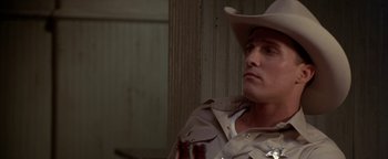 Movie still from “Lone Star” (1996), directed by John Sayles – A man wearing a cowboy hat sitting in front of a wooden wall; Close Up shot, Over the shoulder angle