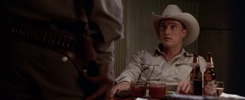 Movie still from “Lone Star” (1996), directed by John Sayles – A man wearing a cowboy hat sitting at a table; Medium shot, Over the shoulder angle