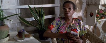 Movie still from “Lone Star” (1996), directed by John Sayles – An older woman sitting at a table with a potted plant; Close Up shot, High angle