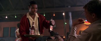 Movie still from “Lone Star” (1996), directed by John Sayles – A man holding a tray with a bottle of beer on top of it; Medium shot, Over the shoulder angle