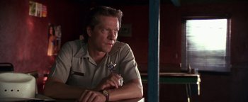 Movie still from “Lone Star” (1996), directed by John Sayles – A man sitting in front of a wooden table; Close Up shot, Low angle