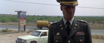Movie still from “Lone Star” (1996), directed by John Sayles – A man in a military uniform standing next to a car; Medium shot, Over the shoulder angle