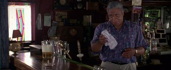 Movie still from “Lone Star” (1996), directed by John Sayles – An older man cleaning a bar with a cloth; Medium shot, Over the shoulder angle