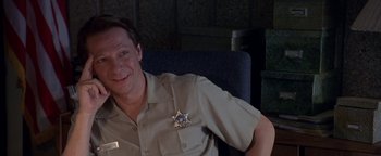 Movie still from “Lone Star” (1996), directed by John Sayles – A man sitting in a chair wearing a sheriff's badge; Close Up shot, High angle