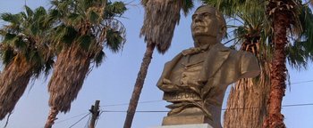 Movie still from “Lone Star” (1996), directed by John Sayles – A statue of a man in a suit and tie next to a palm tree; Close Up shot, Low angle