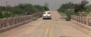 Movie still from “Lone Star” (1996), directed by John Sayles – An old car is driving down the road; Wide shot, High angle