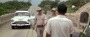 Movie still from “Lone Star” (1996), directed by John Sayles – A couple of men standing next to each other on the side of a road; Wide shot, Over the shoulder angle