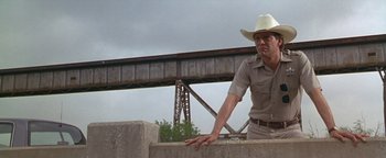 Movie still from “Lone Star” (1996), directed by John Sayles – A man wearing a cowboy hat leaning on a wall; Medium shot, Low angle