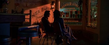 Movie still from “Lone Star” (1996), directed by John Sayles – Two people sitting in chairs in front of a store window; Wide shot, High angle
