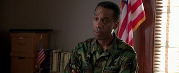 Movie still from “Lone Star” (1996), directed by John Sayles – A man in military fatigues sitting in front of an american flag; Close Up shot, Low angle