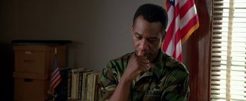 Movie still from “Lone Star” (1996), directed by John Sayles – A man in fatigues sitting in front of an american flag; Close Up shot, High angle