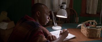 Movie still from “Lone Star” (1996), directed by John Sayles – A man sitting at a table writing on a piece of paper; Close Up shot, High angle