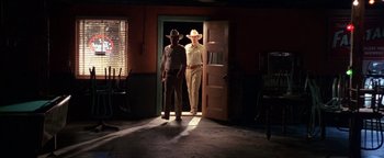 Movie still from “Lone Star” (1996), directed by John Sayles – A couple of men standing next to each other in front of a door; Wide shot, Low angle