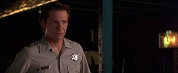 Movie still from “Lone Star” (1996), directed by John Sayles – A man wearing a sheriff's badge stands in front of a building; Close Up shot, Low angle