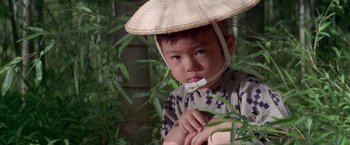 Movie still from “Lone Wolf and Cub: Baby Cart to Hades” (1972), directed by Kenji Misumi – A young boy wearing an asian hat and sitting on a chair; Close Up shot, High angle