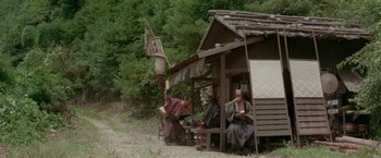 Movie still from “Lone Wolf and Cub: Baby Cart to Hades” (1972), directed by Kenji Misumi – A group of people sitting outside of a house; Wide shot, High angle