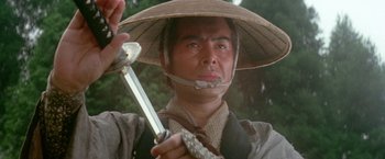 Movie still from “Lone Wolf and Cub: Baby Cart to Hades” (1972), directed by Kenji Misumi – A man holding a sword wearing a straw hat; Close Up shot, Low angle