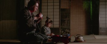 Movie still from “Lone Wolf and Cub: Baby Cart to Hades” (1972), directed by Kenji Misumi – A man and a boy sitting on the floor playing a video game; Medium shot, Low angle