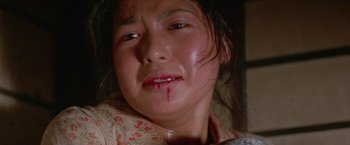 Movie still from “Lone Wolf and Cub: Baby Cart to Hades” (1972), directed by Kenji Misumi – A woman with blood on her face and a knife stuck in her mouth; Close Up shot, High angle